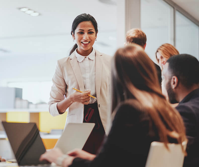 Woman in suit coat speaking to colleagues