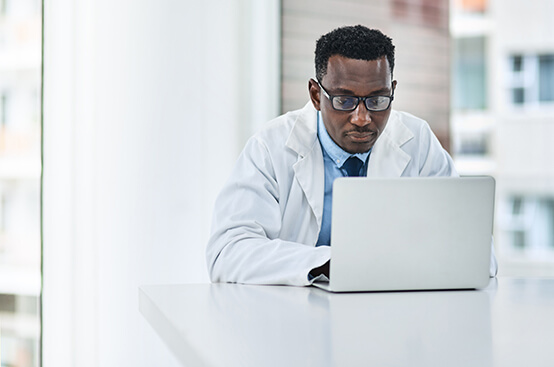 Young male doctor working on laptop