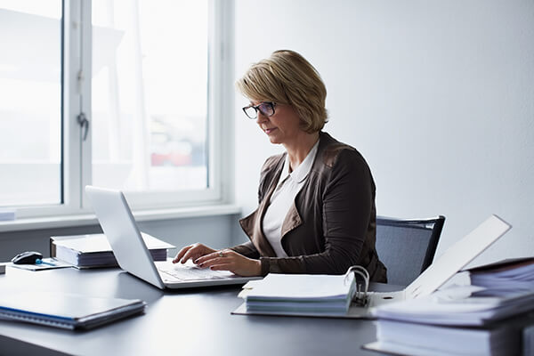 Woman sitting at desk with laptop and binders