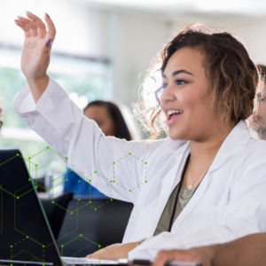 POC female medical resident in white lab coat raising hand with smile in classroom setting.